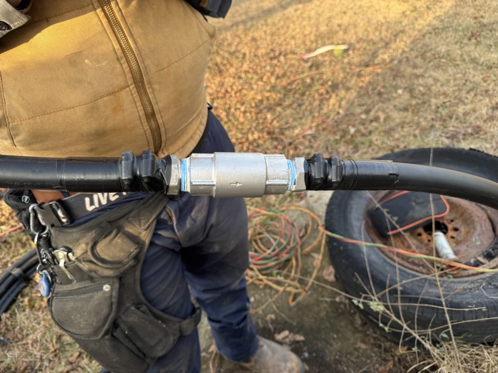 person holding a section of black piping that has been spliced